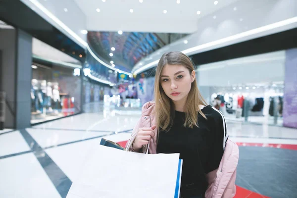 Retrato de una chica con estilo contra un fondo de centro comercial. La chica está de compras en el centro comercial. Una mirada a la cámara . — Foto de Stock
