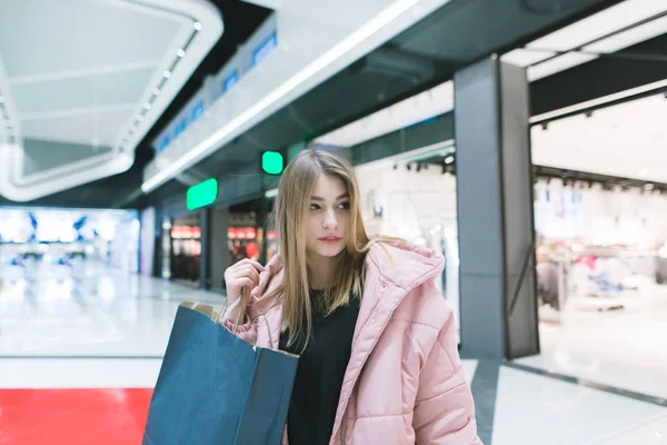 Portréja egy aranyos lány, a kezében egy modern, szép shopping mall bevásárló. Vásárlás koncepció. Vizsgálja meg el. — Stock Fotó