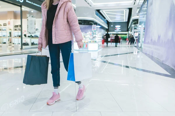 En snygg tjej med shopping i hennes händer går igenom en modern, vacker shoppinggalleria. Flickan shopping. — Stockfoto