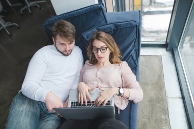 Genç Ofis çalışanları yalan pencereden kanepede ve laptop arıyorum. Ofiste zorla. Hafta içi modern ofis.