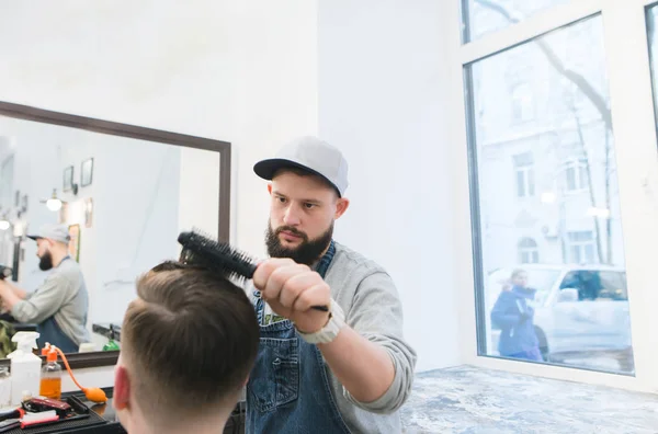 Un coiffeur masculin élégant fait la coiffure d'un homme dans un salon de beauté. Coupe de cheveux élégante dans le salon de coiffure . — Photo