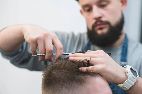 Friseur schneidet einem jungen Mann die Haare. Eine stylische Nase mit der Schere. Arbeit für Friseure aus nächster Nähe — Stockfoto