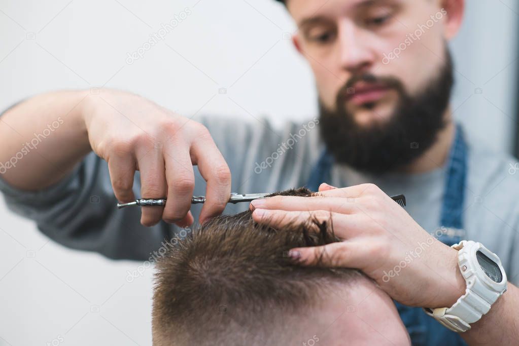 Barber cuts the hair of a young man. Creating a stylish nose with scissors. Work barber's close-up