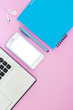 Kulaklıklar, defter ve pembe bir arka plan üstünde not etmek ile smartphone. Üstten Görünüm. Çalışma alanı düz yatıyordu düzeni