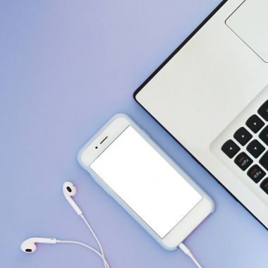 Beyaz bir ekran, bir dizüstü bilgisayar ve mavi bir arka plan üzerinde kulaklık ile bir telefon. Lay becerikli alet düz ve metin için yer.