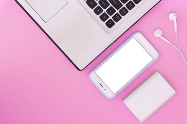 Dizüstü bilgisayar, telefon, kulaklık ve güç bir pembe banka. Düz yatıyordu kompozisyon ve metin için yer. Üstten Görünüm.