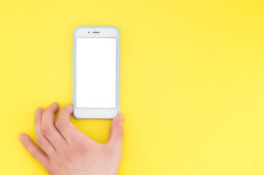 İnsan eli bir akıllı telefon ile sarı bir arka plan üzerinde izole. El telefon tutar. Tasarım şablonu.