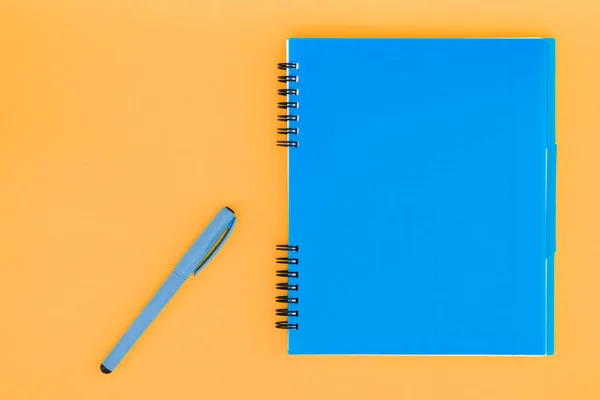 Een blauwe notebook met een handvat op de oranje achtergrond. Plat lag sjabloon. Plaats voor tekst. — Stockfoto