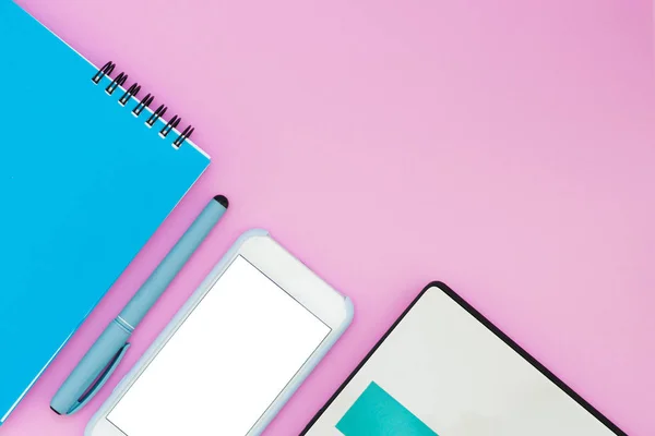 Smartphone, laptop en notitieboekjecomputer op een roze achtergrond. Bovenaanzicht. Werkruimte Flat La lay-out — Stockfoto