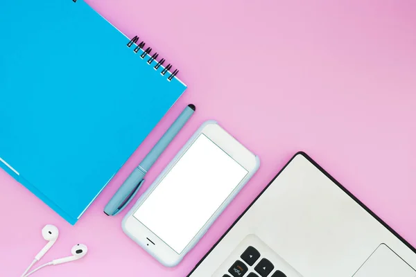 Smartphone con cuffie, notebook e blocco note su sfondo rosa. Vista dall'alto. Spazio di lavoro Piatto Layout laico . — Foto Stock