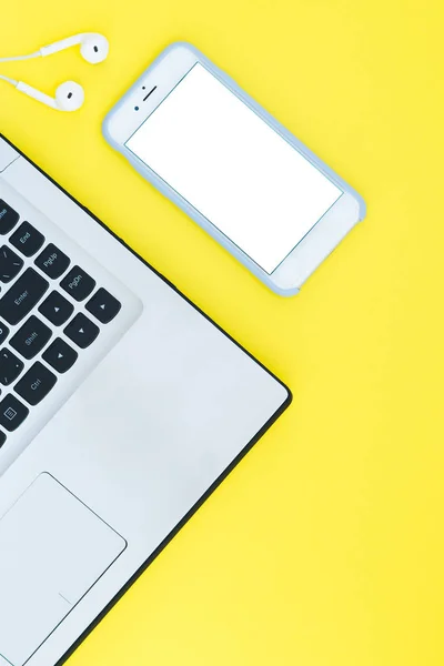 Portátil y smartphone con pantalla blanca y auriculares en el fondo amarillo. Espacio de trabajo minimalista con lugar para el texto. Piso Lay — Foto de Stock