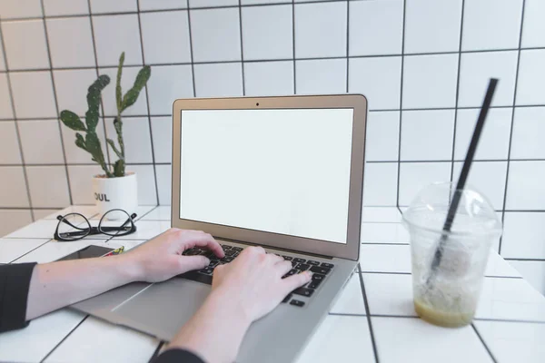 Spazio di lavoro nel bar. Lo studente lavora su un computer portatile con uno schermo bianco nel caffè e beve un frullato. Lavoro freelance . — Foto Stock