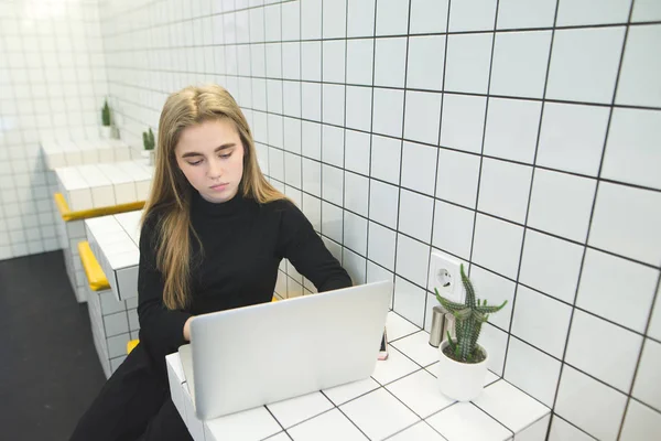 Kız bir modern, şık restoranda bir dizüstü bilgisayarda internet kullanır. Hipster öğrenci kamuya açık bir yerde bir dizüstü bilgisayar üzerinde çalışıyor. Üstten Görünüm — Stok fotoğraf