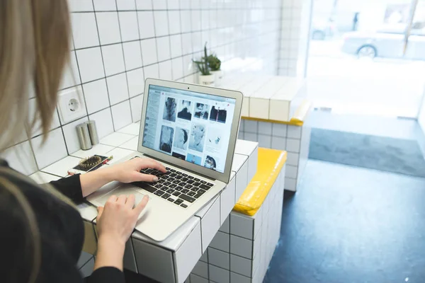 Ein studentisches Mädchen nutzt das Internet auf einem Laptop mit einem stilvollen, hellen Interieur. die Arbeit eines freien Mitarbeiters für einen Laptop in einem Café. — Stockfoto