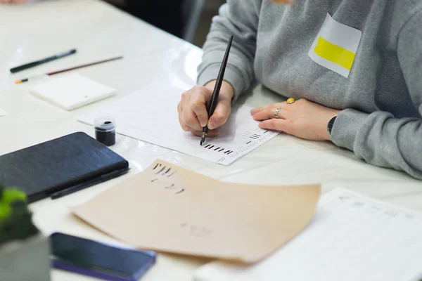 El hombre se practica en caligrafía. Educación Caligrafía. Estudiante escribe pluma y tinta en papel . — Foto de Stock