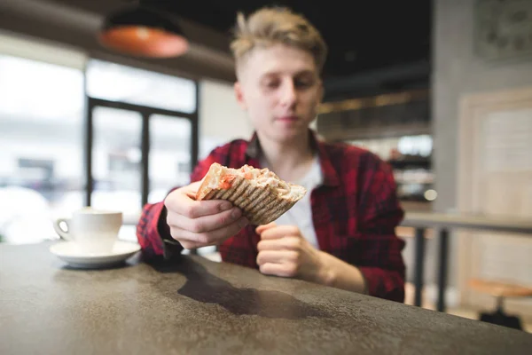 Sándwich de Panini de cerca. Un joven ofrece un sándwich. Estudiante con un sándwich sentado en un café. Concéntrate en el sándwich — Foto de Stock