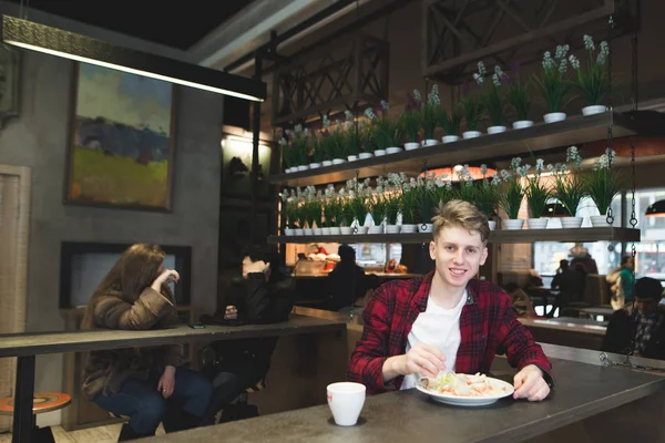 Piękny młody człowiek jedzenie Sałatka z widelcem w kawiarni. Dania studenckie z sałatką w restauracji. Spojrzenie na jedzenie. Pożyteczny obiad. — Zdjęcie stockowe