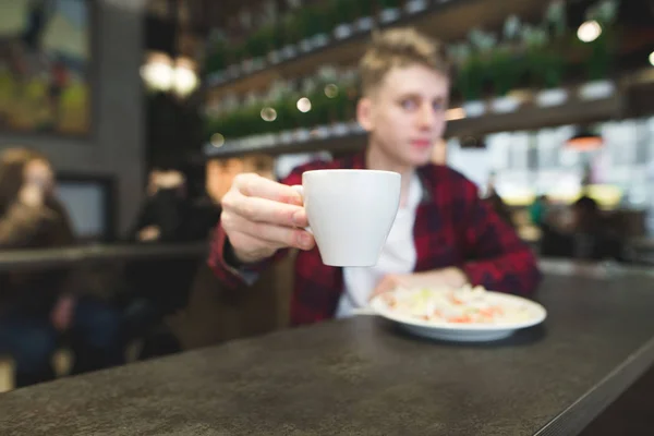 Un joven vierte una taza de café en la cámara. Una taza de café en un truco y primer plano — Foto de Stock