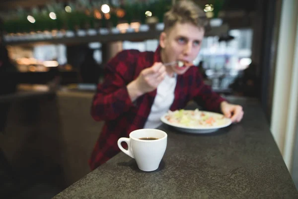 Una taza de café en el fondo de una persona que come un restaurante. La taza está enfocada, la persona está borrosa — Foto de Stock