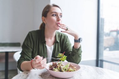 Salata bir restoranda yemek ve vitrinlere bakıyor güzel ve genç birbayan. Bir salata tabağına odaklan. Öğle Yemeği restoranda sağlıklı bir yemek ile