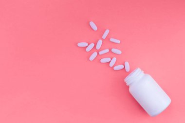 Poured pills and a white can of medicine for a pink pastel background. Flat lay. Top view clipart