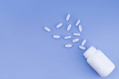 Scattered pills from a bottle on a pastel blue background. Place for text. Flat lay. clipart
