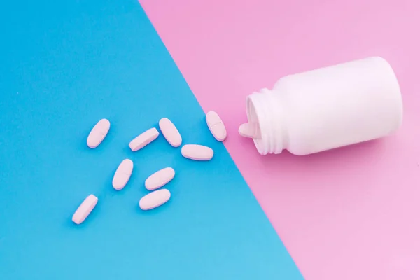 Μακροεντολή φωτογραφία χάπια που χύνει έξω από ένα άσπρο μπουκάλι για ένα παστέλ χρώμα φόντου. Χάπια σε ροζ και μπλε φόντο — Φωτογραφία Αρχείου