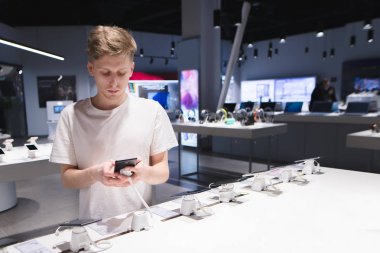 Ciddi bir genç adam elektronik mağazasından bir akıllı telefon satın alıyor. Teknik deposundaki bir akıllı telefon satın almak
