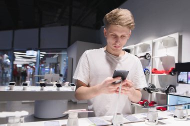 Genç bir adam bir telefon bir elektronik mağazasında kullanır. Mobil Pho