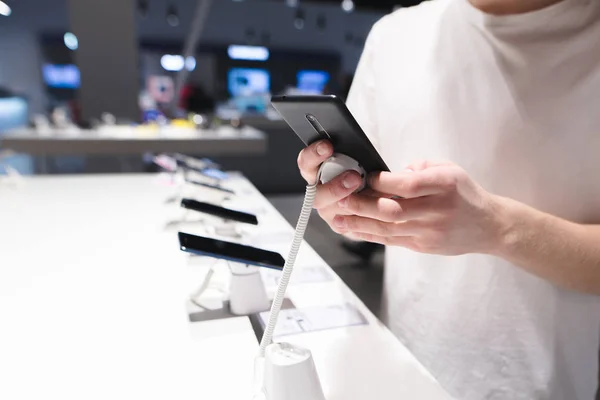 Elegir un smartphone en la tienda de electrónica. Las manos del hombre prueban el teléfono en la tienda. Comprar un smartphone en la tienda de tecnología . — Foto de Stock