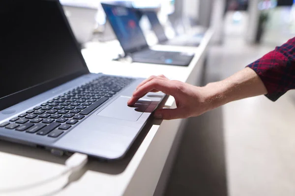L'uomo controlla il computer con un touchpad. La mano di un uomo usa un portatile nel negozio di elettronica. L'acquirente sceglie un computer portatile in un negozio di tecnologia — Foto Stock