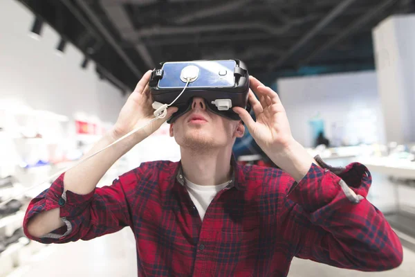 Un jeune homme mignon teste VR sur fond de magasin de technologie — Photo