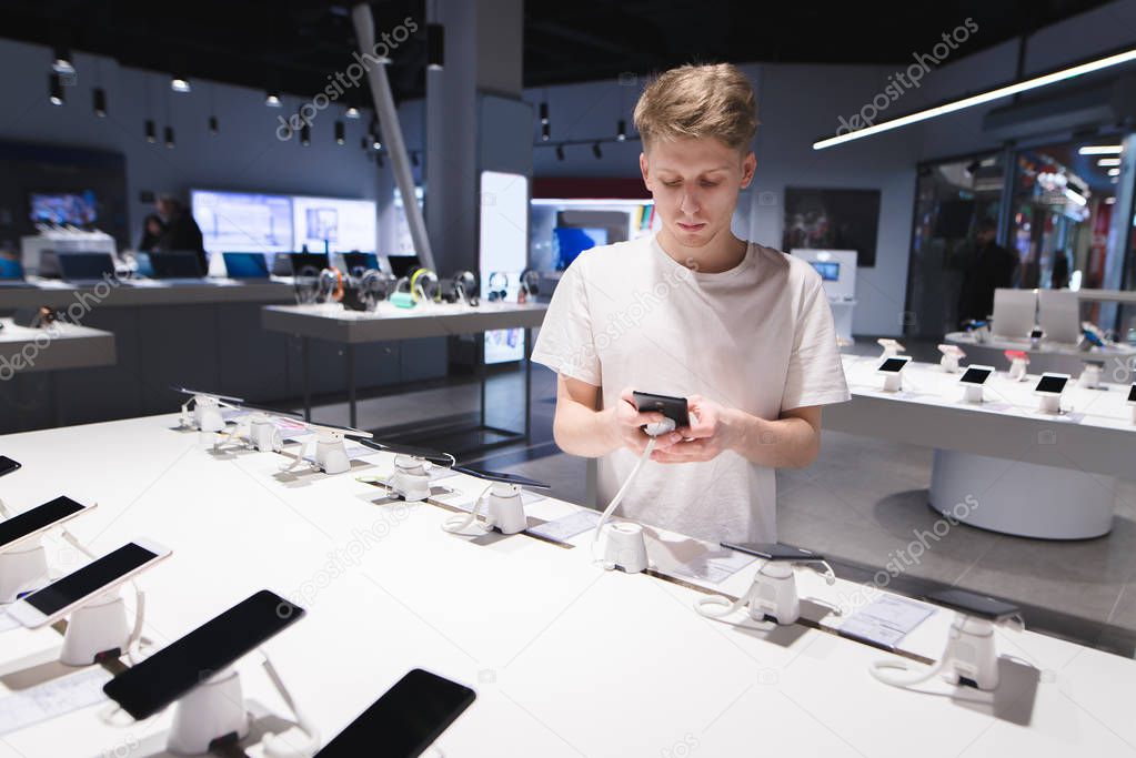 A beautiful student in a white T-shirt looks at smartphones in t