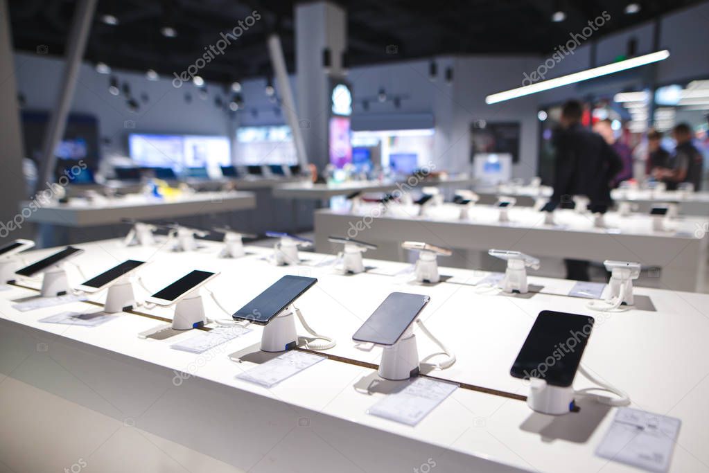 Showcase with smartphones in the modern electronics store. Buy a mobile phone. Many smartphones on the shelf of the technology store