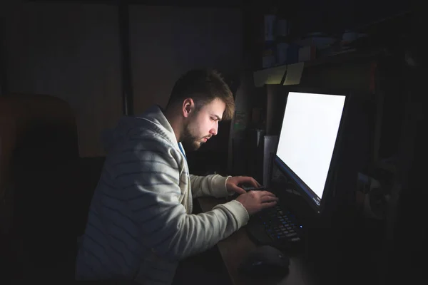 Bir adam evde bir bilgisayar ve çalışma ile oturuyor. Bir adam evde bir bilgisayar yazdırır. Gece iş yerinde bir bilgisayar. — Stok fotoğraf