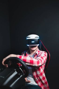 Vr kulaklık üzerinde bir araba simülatörü yarış oyun çalış. Sanal gerçeklik gözlüklü bir adam siyah bir arka plan üzerine bir oyun oynuyor. Geleceğin oyunları