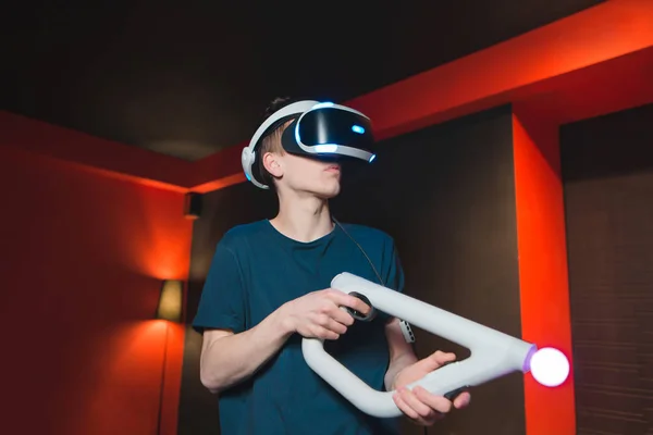 Un jeune homme joue dans des jeux de tir en utilisant le casque VR. Le joueur dans le casque de réalité virtuelle est à l'intérieur et joue à des jeux vidéo . — Photo