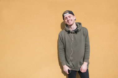 Parlak bir turuncu duvar arka plan üzerinde kulaklık ile ayakta gülümseyen güzel öğrenci