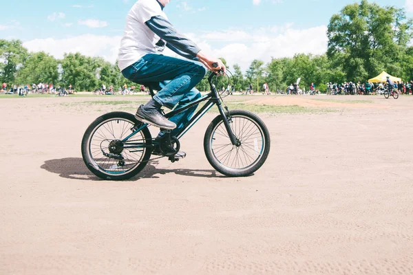 Un uomo guida una piccola mountain bike in una giornata di sole estivo. Passeggiata intorno al parco in bicicletta. Uomo adulto in bicicletta per bambini . — Foto Stock