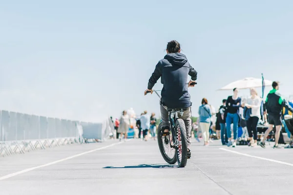 The back of the cyclist. A man rides on an asphalt on a bicycle on a background of people. A bicycle ride from behind. City bike. — Stock Photo, Image