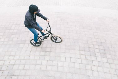 Genç bir adam bir Bmx arka tekerlek üzerinde Bisiklete binmek rahat giyim. Üstten Bmx bisikletçi minimalist fotoğraf olduğunu. BMX kültür