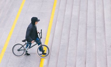 Şık bir genç adam bir merdiven ile Bmx Bisiklet tarafından elinde tırmanıyor. Bir bisiklet ile yürümek. BMX kavramı. Sokak kültürü