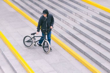 Bmx motorcu merdivenlerde ayakta ve yan yana arıyorum. Üstten Görünüm. Bir bisiklet ile yürümek. Sokak kültürü