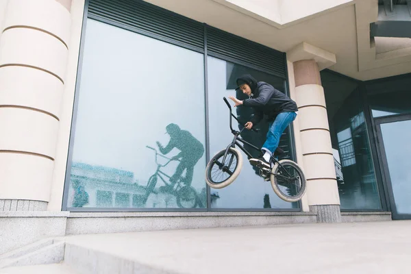 En ung man gör tricks på Bmx mot bakgrund av arkitekturen. En pojke hoppar på en Bmx cykel — Stockfoto