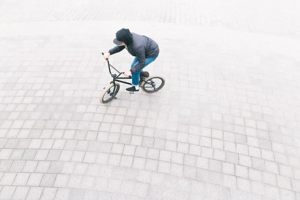 Een man rijdt een Bmx fiets op een stoep overhead. Minimalistische foto van wielrenner die op Bmx op het plein rijdt — Stockfoto