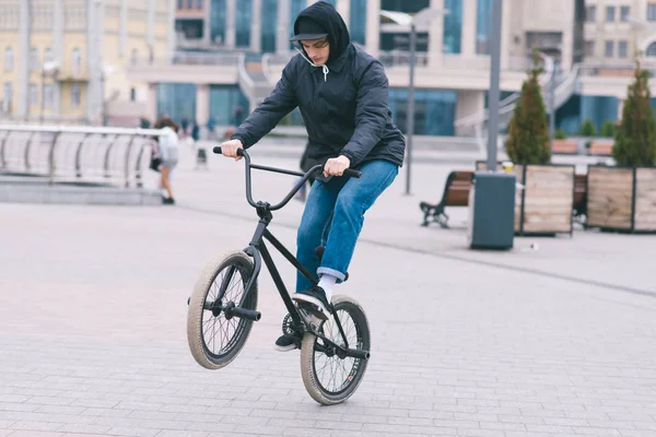 The teen does tricks on the BMX. BMX cyclist rides a bike around the park and makes tricks. BMX concept — Stock Photo, Image