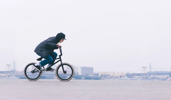 Cultura de rua. Jovem BMX cavaleiro andando de bicicleta em um fundo minimalista da cidade. BMX ciclista vai fazer um truque. Conceito de BMX — Fotografia de Stock