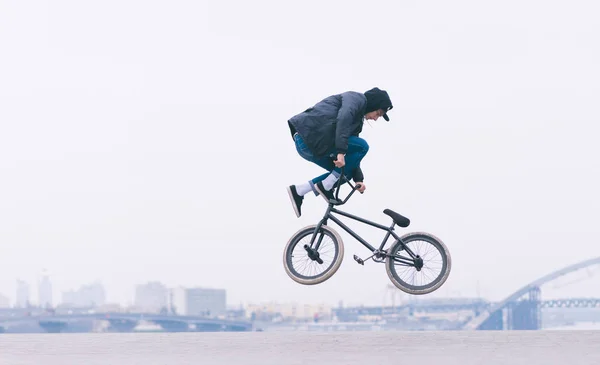 En ung man gör ett Tailwhip trick i luften på en Bmx-cykel. BMX trick mot bakgrund av minimalistisk stadslandskap. Bmx freestyle — Stockfoto