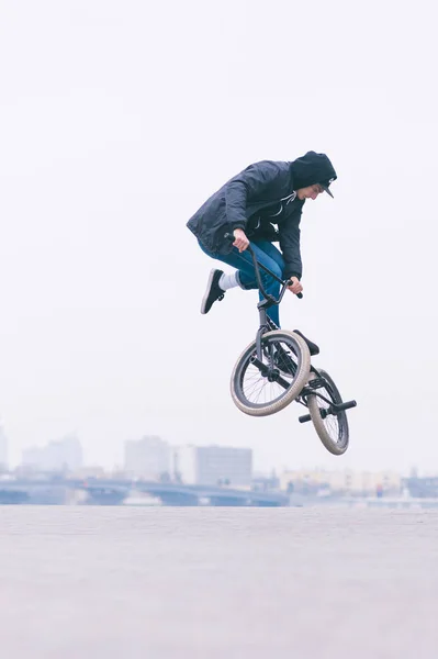 Un giovanotto che fa trucchi con una bici BMX. BMX freestyle sullo sfondo del paesaggio urbano — Foto Stock