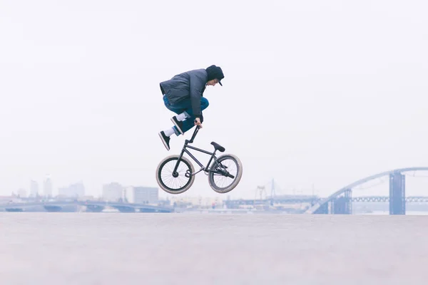 Young BMX bicycle reader does tricks in the air against the background of the urban landscape. BMX freestyle. Street culture — Stock Photo, Image